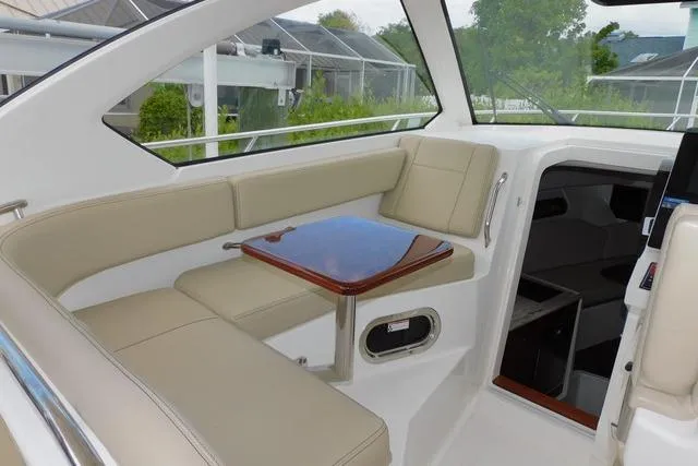 Yacht Photos Pics 2019 Pursuit OS 325 Offshore boat interior with beige seating and wooden table.