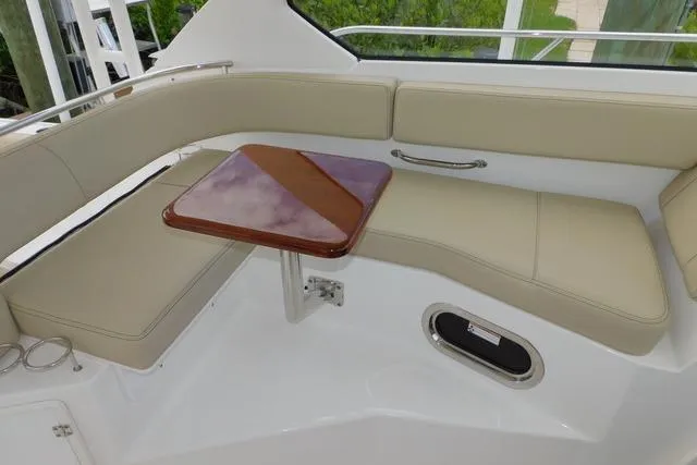  Yacht Photos Pics 2019 Pursuit OS 325 Offshore boat interior with beige seating and wooden table.