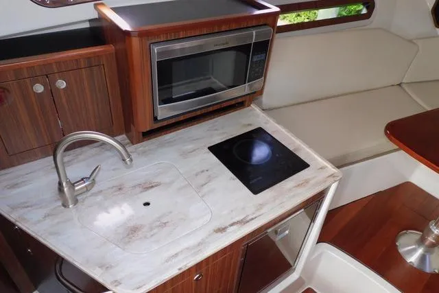 Yacht Photos Pics 2019 Pursuit OS 325 Offshore boat kitchen with sink, stove, and microwave.