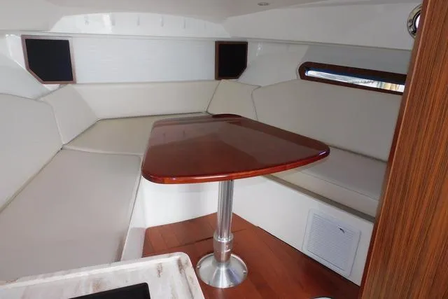  Yacht Photos Pics 2019 Pursuit OS 325 Offshore cabin with elegant wood table and cushioned seating.