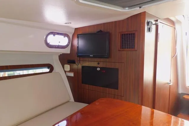  Yacht Photos Pics 2019 Pursuit OS 325 Offshore cabin interior with TV and seating area.