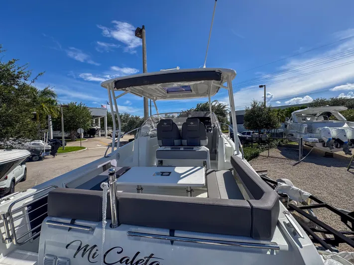 Mi Caleta Yacht Photos Pics 2023 Jeanneau Leader 9.0 WA boat with seating area, docked under clear blue sky.