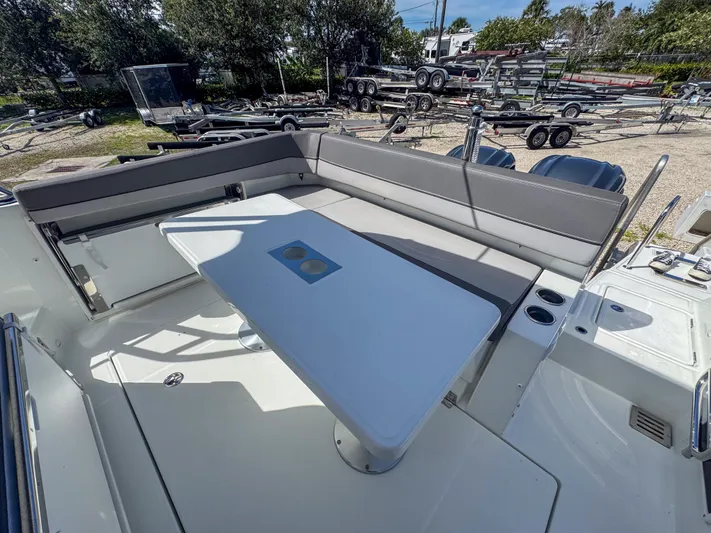 Mi Caleta Yacht Photos Pics 2023 Jeanneau Leader 9.0 WA boat interior with seating and table, parked on a trailer.