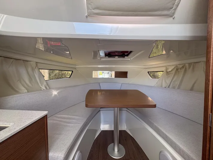 Mi Caleta Yacht Photos Pics Interior of 2023 Jeanneau Leader 9.0 WA boat with cozy seating and wooden table.
