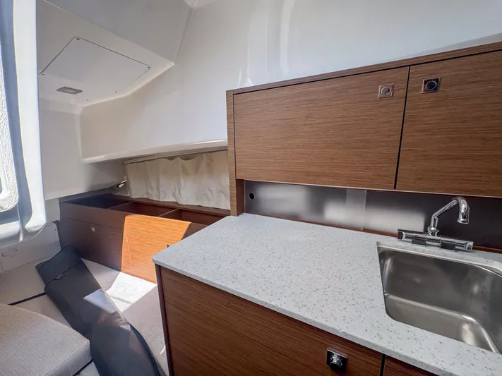 Mi Caleta Yacht Photos Pics Interior of 2023 Jeanneau Leader 9.0 WA boat with modern kitchenette and wood cabinetry.