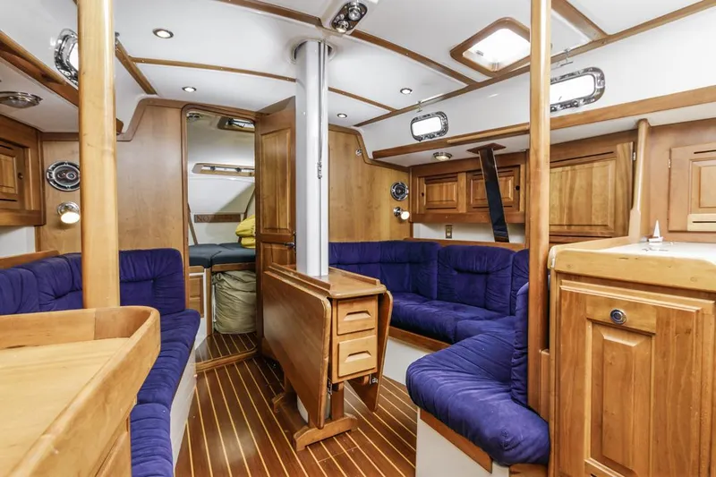 Kamala Yacht Photos Pics Luxurious interior of 2003 Tartan 3700 sailboat with wooden finish and blue seating.