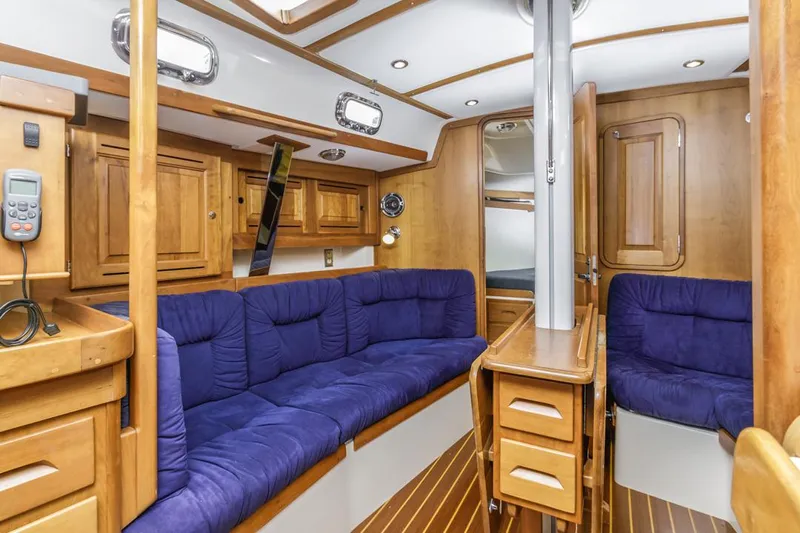 Kamala Yacht Photos Pics Interior of 2003 Tartan 3700 sailboat with wooden cabinetry and blue cushioned seating.