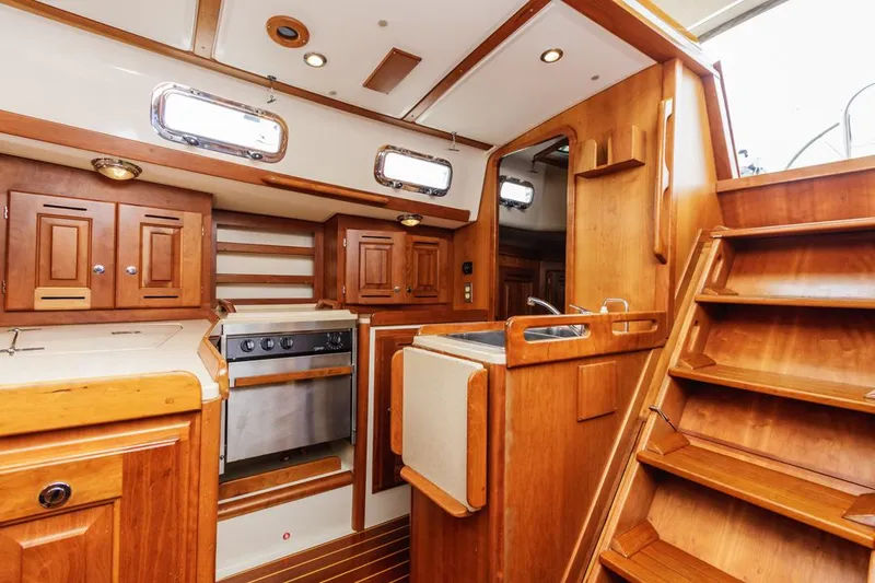 Kamala Yacht Photos Pics Interior of 2003 Tartan 3700 sailboat with wooden cabinetry and compact kitchen area.