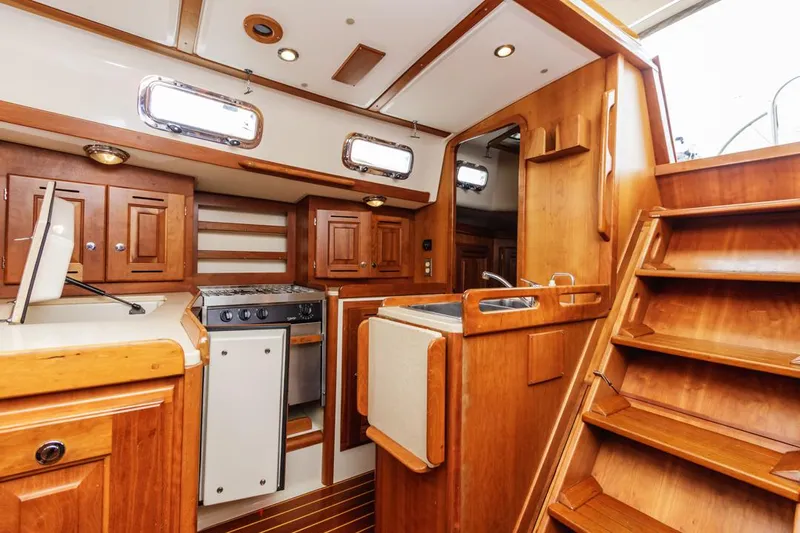 Kamala Yacht Photos Pics Interior of 2003 Tartan 3700 sailboat with wooden cabinetry and compact kitchen area.