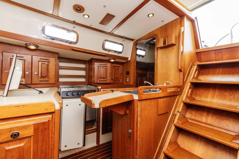 Kamala Yacht Photos Pics Interior of 2003 Tartan 3700 sailboat with wooden cabinetry and compact kitchen area.