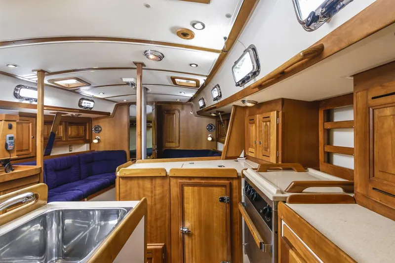 Kamala Yacht Photos Pics Interior of 2003 Tartan 3700 sailboat with wooden cabinetry and blue seating.
