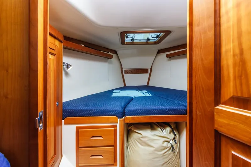 Kamala Yacht Photos Pics Cozy cabin interior of 2003 Tartan 3700 sailboat with wooden finish and blue bedding.