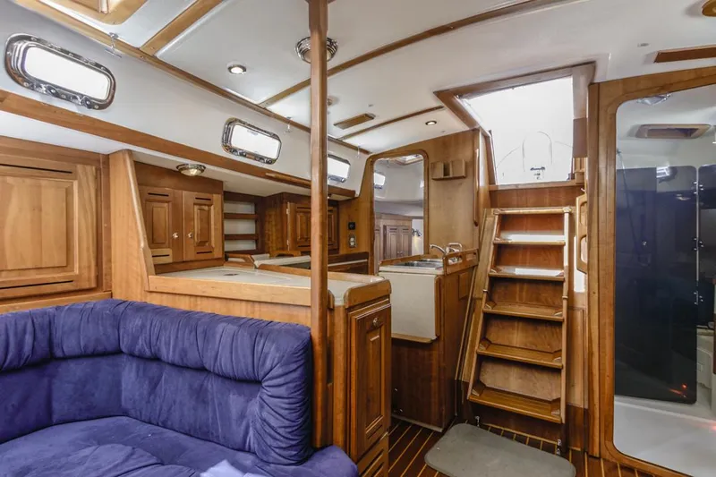 Kamala Yacht Photos Pics Interior of 2003 Tartan 3700 sailboat with wooden cabinetry and blue seating.