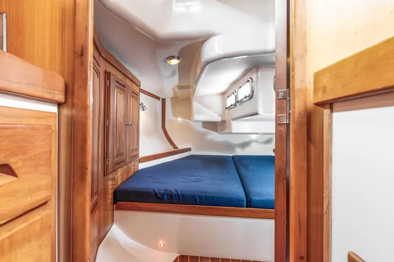 Kamala Yacht Photos Pics Cozy cabin interior of 2003 Tartan 3700 sailboat with wooden accents and blue bedding.