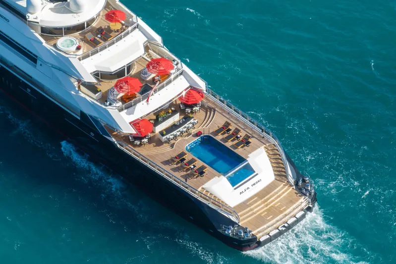Alfa Nero Yacht Photos Pics Luxurious 2007 Oceanco 269' yacht with pool, sun loungers, and red umbrellas cruising in blue ocean.