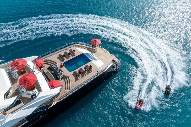 Alfa Nero Yacht Photos Pics Luxurious 2007 Oceanco 269' yacht with pool, red umbrellas, and jet skis in blue ocean.