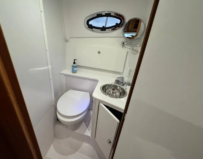 Omega Yacht Photos Pics 2022 True North 34 Outboard Express bathroom with toilet, sink, and porthole window.