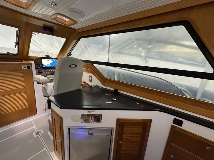 Omega Yacht Photos Pics 2022 True North 34 Outboard Express interior with helm, navigation system, and wooden cabinetry.