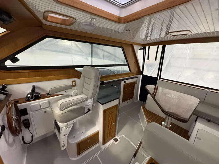 Omega Yacht Photos Pics 2022 True North 34 Outboard Express interior with helm, seating, and wooden accents.