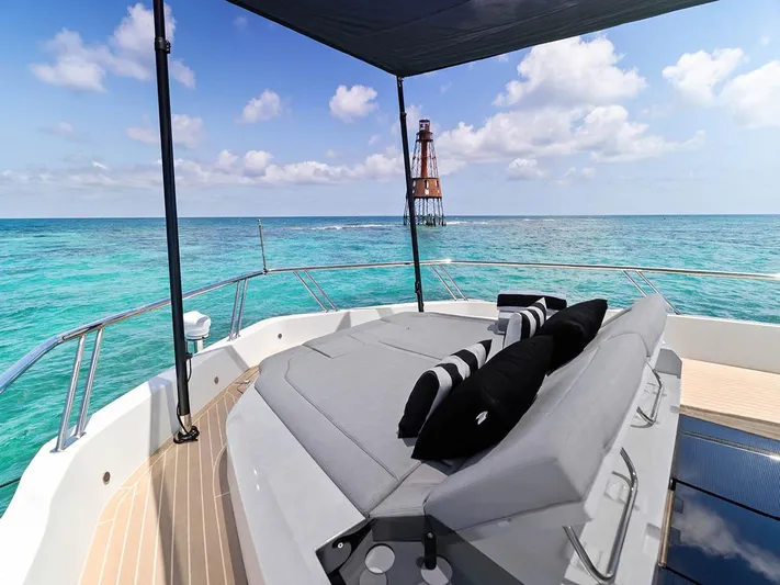 Dad Bod Yacht Photos Pics Luxurious 2024 Galeon 560 Fly yacht with sunbed, ocean view, and lighthouse in the distance.