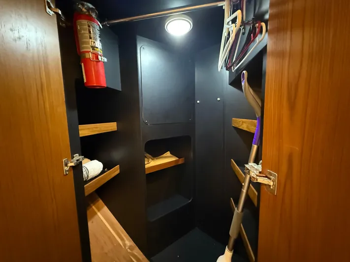  Yacht Photos Pics Storage closet in 2014 Tiara Yachts 4500 Sovran, featuring shelves, hangers, and a fire extinguisher.