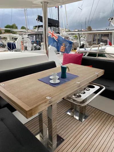 Finisterre Yacht Photos Pics Outdoor dining area on a 2017 Lagoon 52 F yacht with wooden table and nautical decor.