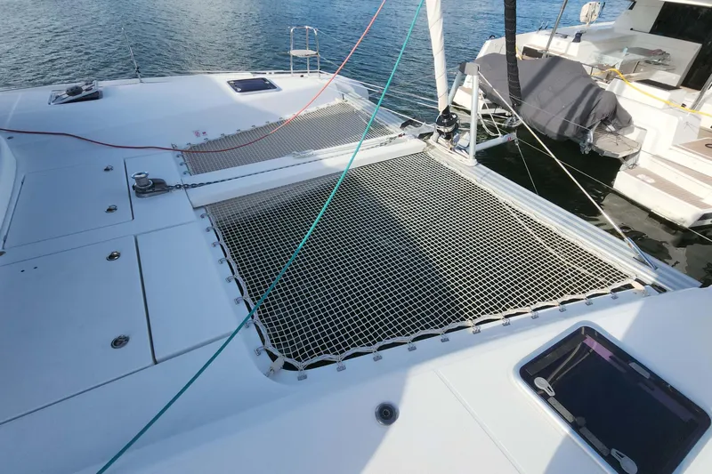  Yacht Photos Pics 2020 Lagoon 42 catamaran deck with netting, docked on calm water.