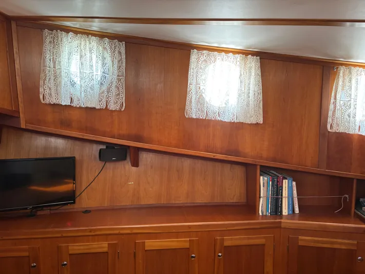 Diesel Duck Yacht Photos Pics Interior of 1999 Diesel Duck Trawler with wood paneling, lace curtains, TV, and books.