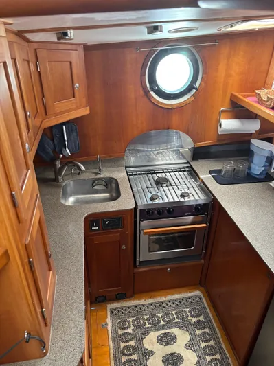 Diesel Duck Yacht Photos Pics 1999 Diesel Duck Trawler kitchen with stove, sink, and wooden cabinetry.