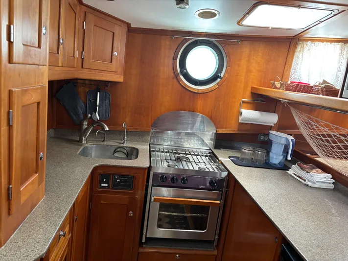 Diesel Duck Yacht Photos Pics 1999 Diesel Duck Trawler kitchen with wooden cabinets, stove, and porthole window.