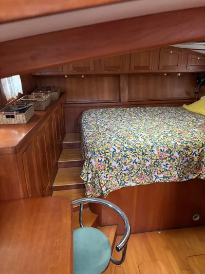 Diesel Duck Yacht Photos Pics 1999 Diesel Duck Trawler cabin with floral bedspread, wooden cabinetry, and a chair.