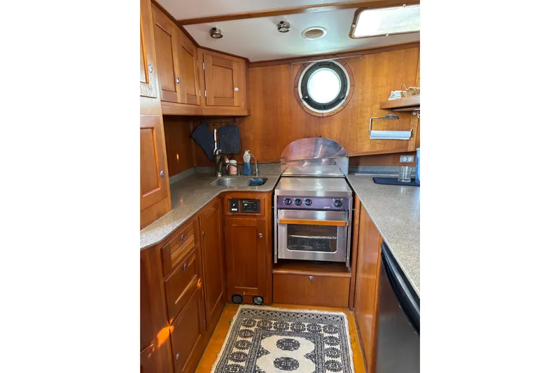 Diesel Duck Yacht Photos Pics 1999 Diesel Duck Trawler kitchen with wooden cabinets, stove, and porthole window.