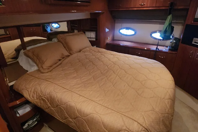  Yacht Photos Pics Luxurious bedroom interior of 2005 Carver 466 Motor Yacht with cozy bedding and wood cabinetry.