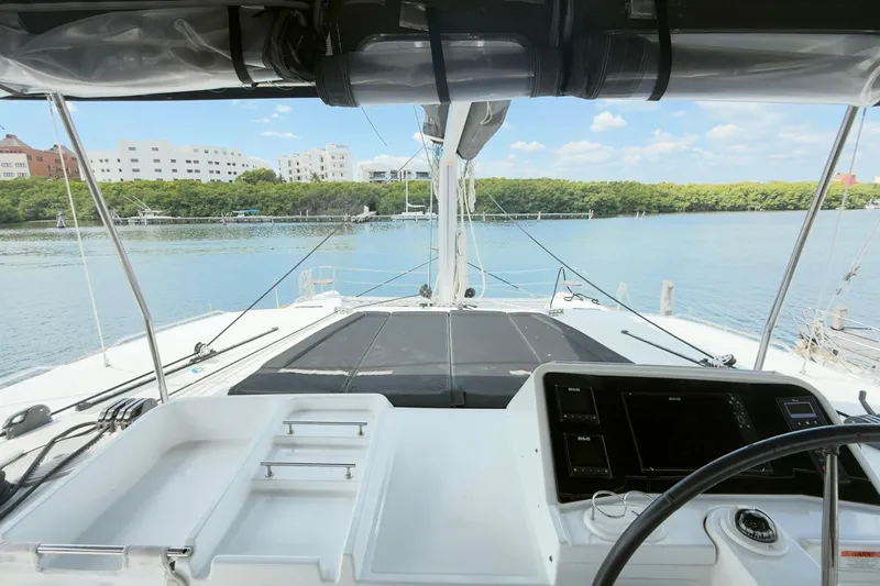 Carpediem 2 Yacht Photos Pics Cockpit view of 2019 Lagoon 450 catamaran, overlooking serene waters and distant buildings.