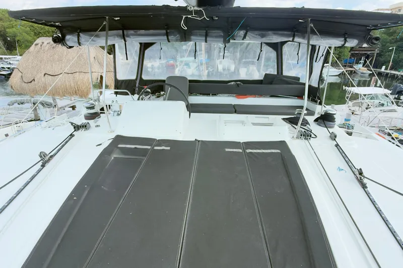 Carpediem 2 Yacht Photos Pics 2019 Lagoon 450 catamaran deck with seating and canopy in marina setting.