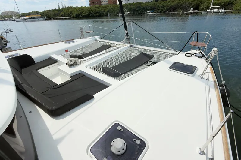 Carpediem 2 Yacht Photos Pics 2019 Lagoon 450 catamaran deck with seating and netting, docked by a calm waterfront.