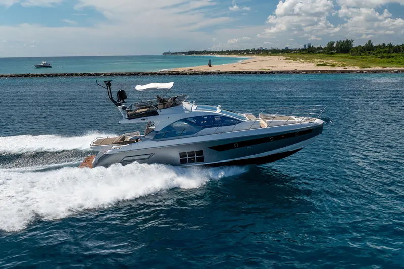  Yacht Photos Pics 2021 Azimut S6 Sportfly yacht cruising on blue ocean near sandy coastline.