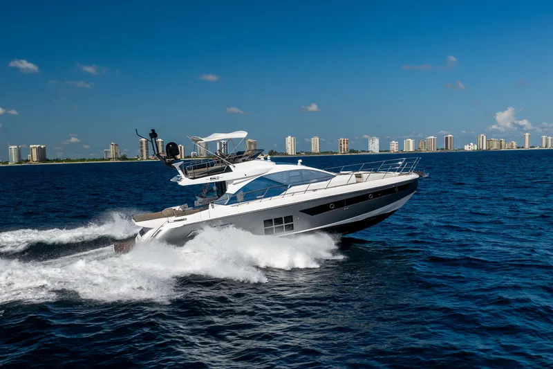  Yacht Photos Pics 2021 Azimut S6 Sportfly yacht cruising on open water with city skyline backdrop.