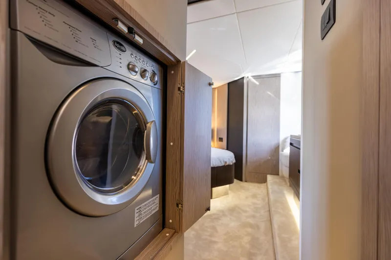  Yacht Photos Pics Laundry area inside 2021 Azimut S6 Sportfly yacht, featuring a compact washing machine.