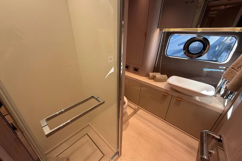  Yacht Photos Pics Luxurious bathroom interior of 2026 Cranchi 62 yacht with modern fixtures and porthole window.