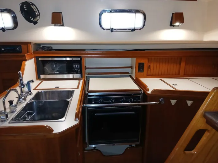 Wonderwind Yacht Photos Pics 1999 Island Packet 45 yacht kitchen with sink, stove, and microwave in wooden cabinetry.