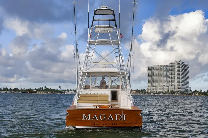 Magadi Yacht Photos Pics 2015 Ritchie Howell Express yacht on water, cityscape background, cloudy sky.