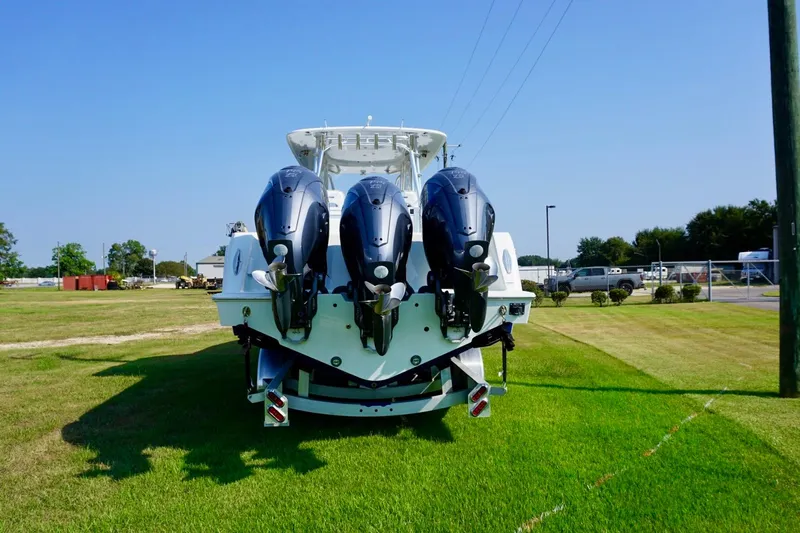 Yacht Photos Pics 2022 Contender 39 Fisharound boat with triple outboard engines on grassy area.