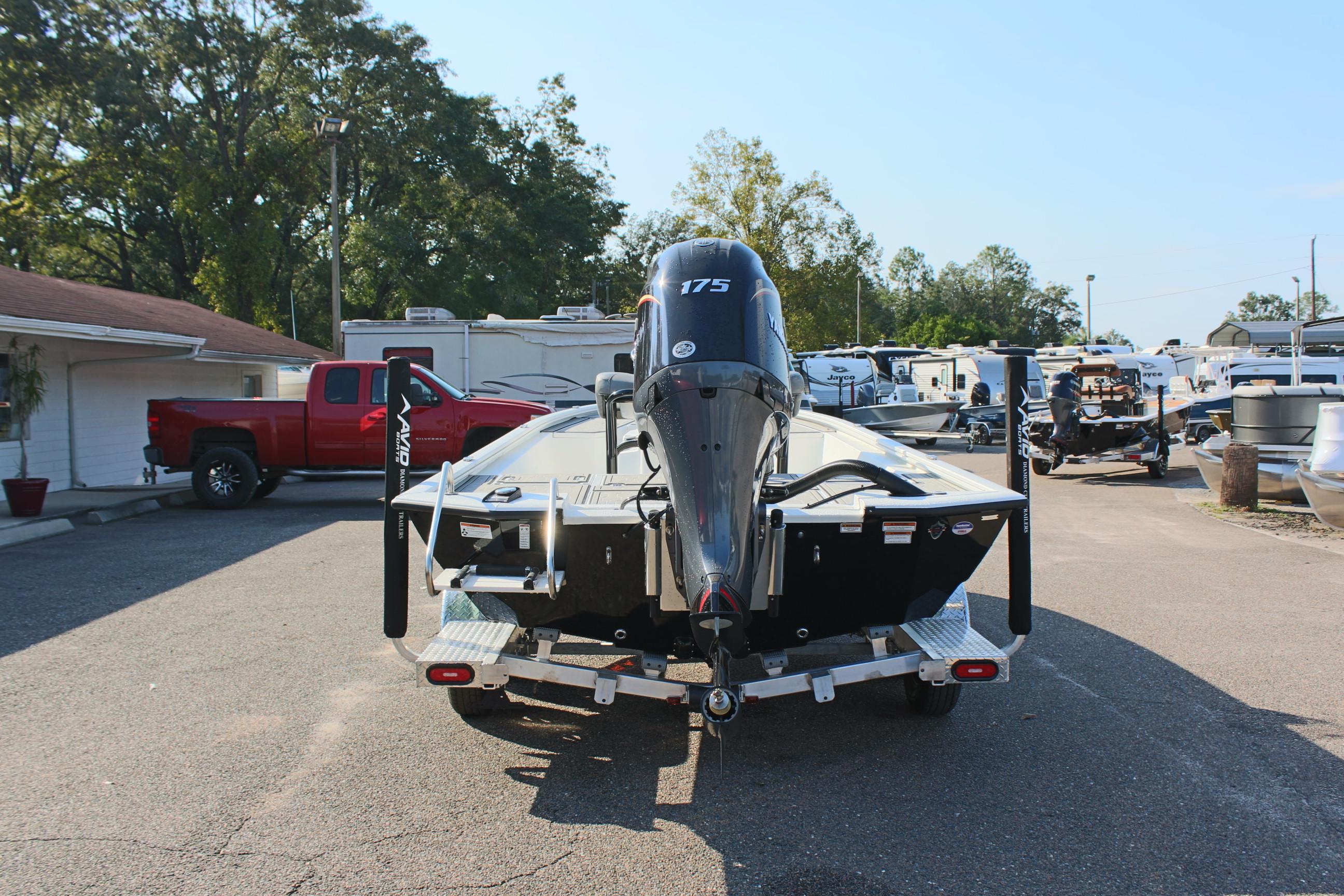 2025 Avid 23 FSX boat with 175 HP engine on trailer in parking lot.
