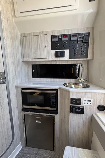 37-039 Yacht Photos Pics Compact kitchen area in a 2025 Regulator 37 boat with microwave, sink, and control panels.