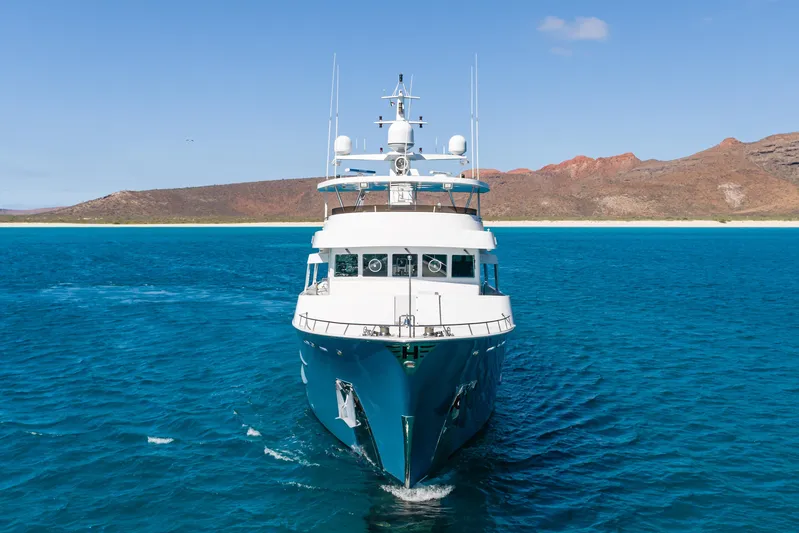 Huracan Yacht Photos Pics Front view of 1991 Delta Marine Expedition yacht on blue ocean near rocky coastline.