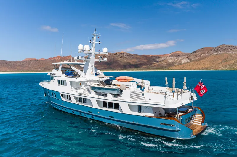 Huracan Yacht Photos Pics Luxurious 1991 Delta Marine Expedition yacht cruising in clear blue waters near scenic coastline.