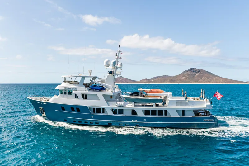 Huracan Yacht Photos Pics Expedition yacht by Delta Marine, 1991, cruising in clear blue waters near an island.