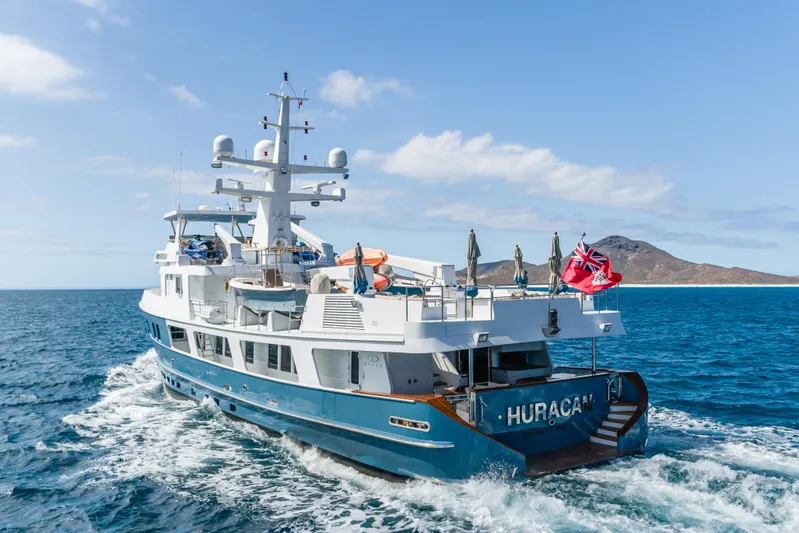 Huracan Yacht Photos Pics Delta Marine Expedition yacht, 1991 model, cruising in open sea near a mountainous island.