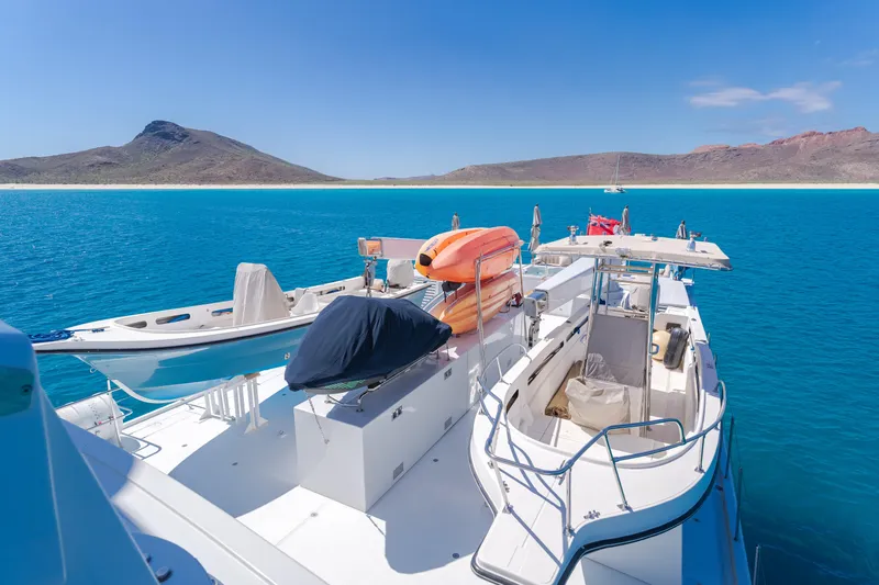 Huracan Yacht Photos Pics Delta Marine Expedition yacht, 1991, anchored in clear blue waters with scenic mountain backdrop.